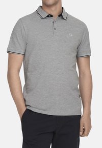 Graues Poloshirt mit schwarzem Kragen und passendem Besatz, kurzen Ärmeln und einem schlichten Logo auf der Brust. Weicher Stoffeindruck.