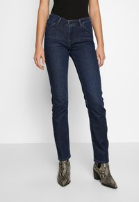 Mörkblå denim jeans med slim fit, fem fickor och medelhög midja. Kombinerade med texturerade ankelskor i ormskinnsmönster.