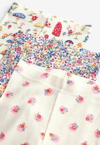 Tre paia di leggings con fantasia: uno con funghi e fiori, uno con stampa floreale e uno con disegni di fiori rotondi su uno sfondo chiaro.