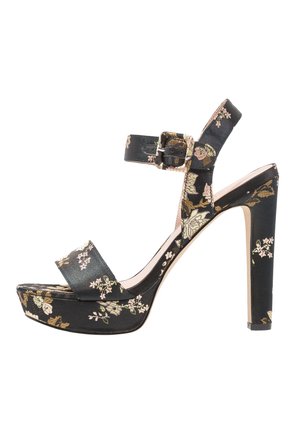 Sandale à talon haut noire à motifs floraux avec bride à la cheville, fermeture à boucle et semelle compensée, présentant des motifs de fleurs roses et beiges.
