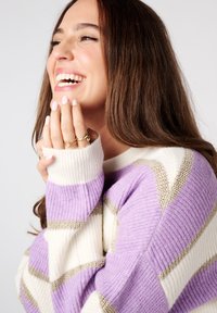 Gebreide trui in wit en lila met metallic gouden strepen, met een wijde halslijn en ribgebreide manchetten. Soepele textuur en een relaxte pasvorm.