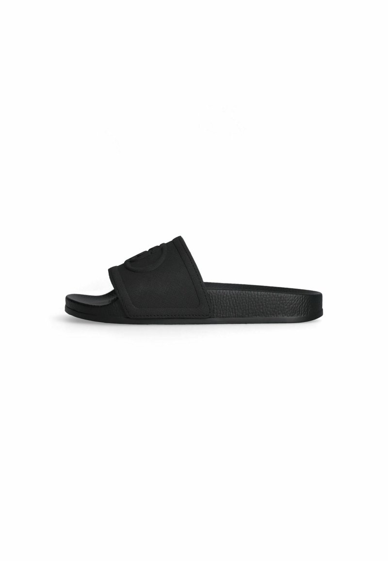 Black slide sandal with a textured material, featuring a wide strap with a raised logo accent and a flat rubber sole.
