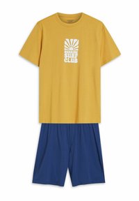 Żółta bawełniana koszulka z białą grafiką "SUNRISE SURF CLUB"; w połączeniu z niebieskimi szortami z elastycznym paskiem.