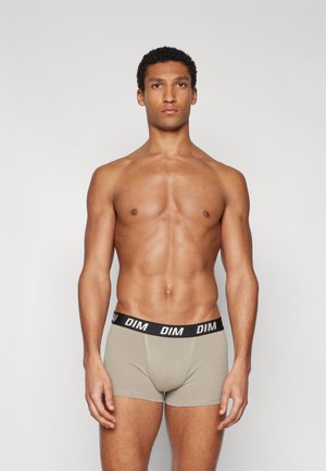 Beige Boxershorts mit einem schwarzen Bund, der den Markennamen "DIM" trägt. Der Stoff scheint weich zu sein und hat eine eng anliegende Passform.