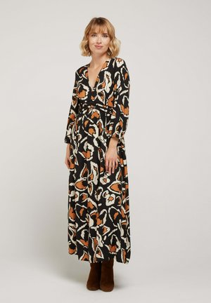 Robe maxi avec un motif abstrait noir, blanc et orange. Décolleté en V, manches longues, taille cintrée et jupe fluide avec une texture douce.
