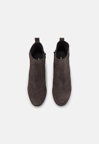 Tmavě hnědé semišové kotníkové boty s elegantním designem, s hladkou texturou, bočními zipy a minimalistickými poutky nahoře.