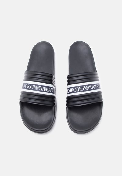 Μαύρα σανδάλια με υφασμένους ιμάντες, με λευκή ταινία λογοτύπου Emporio Armani στο πάνω μέρος, σε απλό λευκό φόντο.