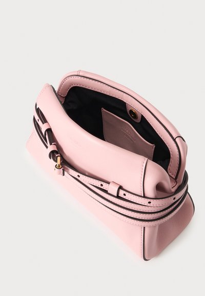 Sac à main en cuir rose doux avec bandoulière réglable, ouverture supérieure dévoilant l'intérieur noir et une petite poche à l'intérieur, sur un fond neutre.
