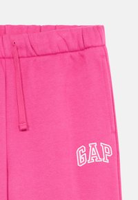 Ροζ φόρμες με ελαστική μέση, κορδόνι και το λευκό λογότυπο "GAP" εκτυπωμένο στην κάτω αριστερή πλευρά. Μαλακό, βαμβακερό υλικό.
