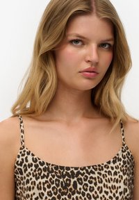 Leopardprint hemdenkraag met dunne bandjes, kenmerkend een lichtbeige achtergrond en donkere bruine vlekken, met een gladde textuur en een ontspannen pasvorm.