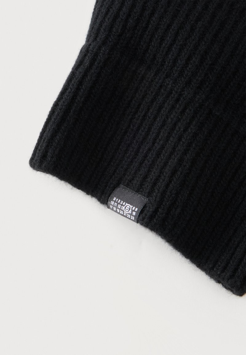 Schwarze gerippte Strickmütze mit kleinem schwarzem Etikett mit weißen Zahlen von 0 bis 23 und einer eingekreisten Zahl 6.