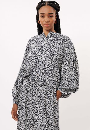 Blumenbluse in Marineblau und Weiß, mit durchgehender Knopfleiste, weiten Ärmeln und einem strukturierten Stoff mit einem dezenten Muster.