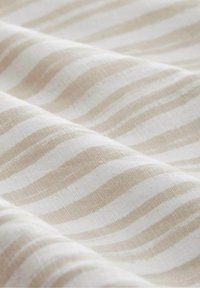 Tissu doux avec des rayures horizontales beige et blanches, montrant la texture et de légers plis.