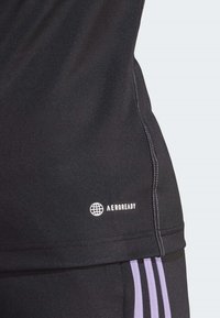 Maglia atletica nera con tessuto testurizzato, con logo "AEROREADY" bianco e strisce viola a contrasto lungo la cucitura laterale.