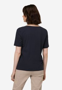 Marineblauwe T-shirt met korte mouwen en een wijde halslijn, versierd met een textuurpatroon op de schouders, gemaakt van zachte katoenstof.