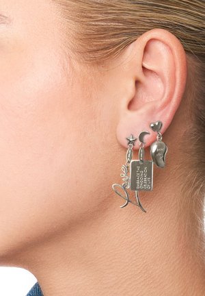 Boucles d'oreilles en argent ornées d'une étoile, d'une lune croissante, d'un cœur et d'une étiquette gravée avec du texte. Des motifs intriqués ajoutent de la texture et un intérêt visuel.