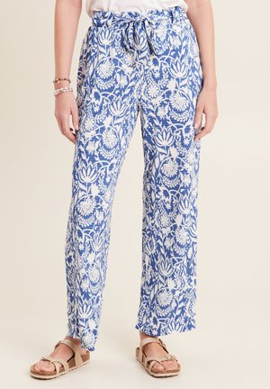Leichte, blau-weiße gemusterte Hosen mit entspanntem Schnitt, ausgestattet mit einem Kordelzugbund und floralem Design. Flache Schuhe werden getragen.