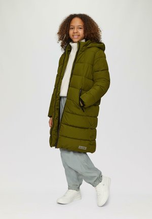 Olijfgroen pufferjack met horizontale doorstikking, capuchon, twee zijzakken en merkpatch; gecombineerd met lichtgrijze broek en witte sneakers.