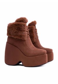Stivaletti alla caviglia con plateau marroni, rifiniti con pelliccia sintetica e design con lacci. Realizzati in morbido camoscio, presentano un tacco a blocco ampio.