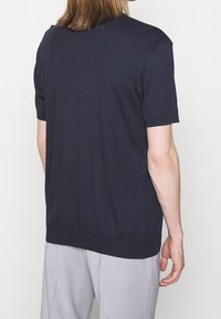 Chemise à manches courtes bleu marine en tissu doux, avec un design simple, une coupe droite et sans logos ni motifs visibles au dos.