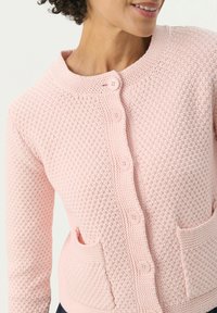 Light pink knitted cardigan with a textured pattern, round neckline, six button closure, and two front pockets.