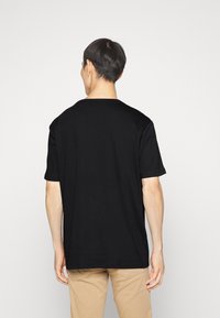 T-shirt nero a maniche corte realizzato in cotone. Presenta un collo rotondo e una vestibilità comoda, senza loghi o motivi visibili.