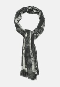 Écharpe à motifs noir et blanc en tissu léger, avec des designs abstraits et des bords à franges, enroulée en boucle.