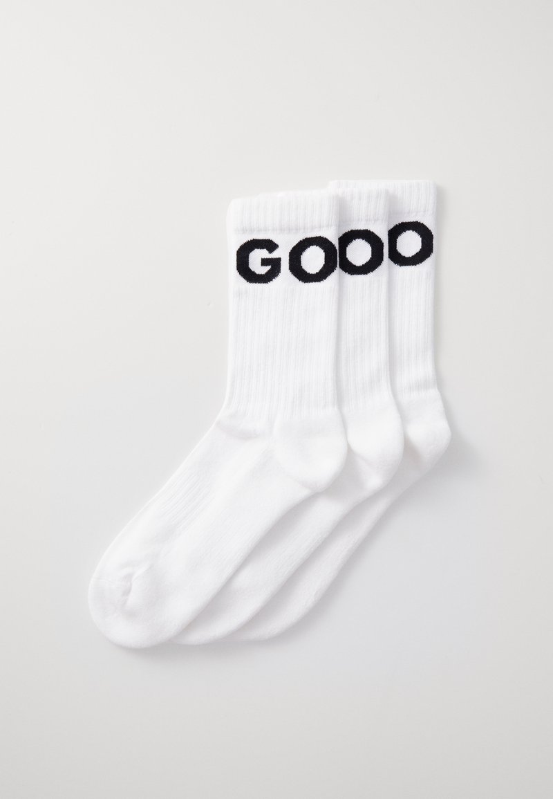 Trois chaussettes blanches en mélange de coton, avec le texte noir brodé "GOOO" sur le revers. Texture côtelée, design jusqu'au genou.
