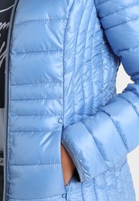 Hellblaues Daunenjacke mit horizontalem Steppmuster, Reißverschluss und elastischen Bündchen. Glattes, glänzendes Material.