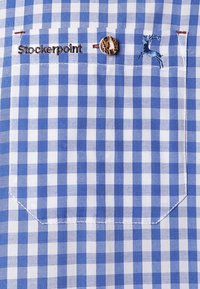Tela de camisa a cuadros azul y blanca con un bolsillo en el pecho. Presenta un logo bordado "Stockerpoint" y un detalle de botón marrón.