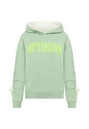 Groene sweatshirt met capuchon, met "OPTIMISME" in fel geel-groene tekst. Lange mouwen met geplooide details en lintaccenten.