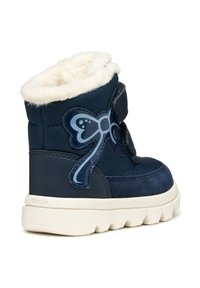 Botas para niño de color azul marino con un suave forro de piel sintética blanca, correa de velcro y un diseño de lazo azul brillante en el lateral. Suela gruesa blanca.