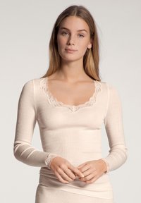 Lichtbeige langemouwen top met kantafwerking bij de hals en mouwuiteinden, voorzien van een geribbelde textuur en een aansluitend ontwerp.