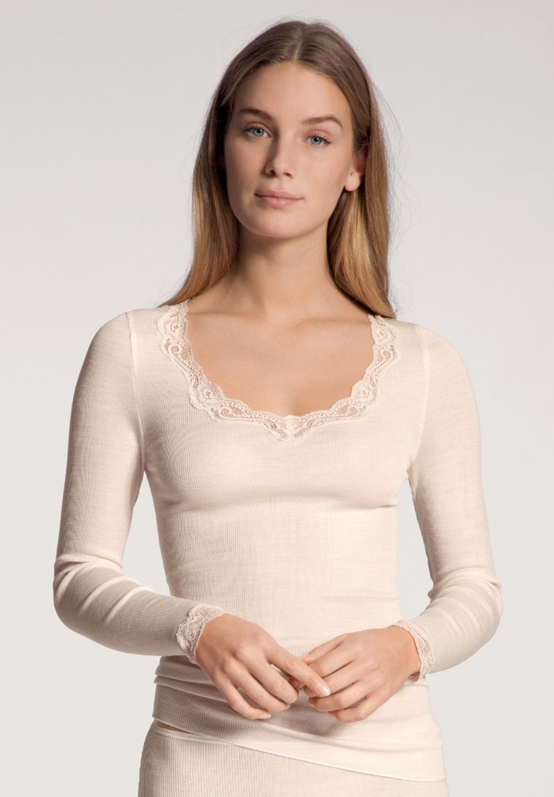 Lichtbeige langemouwen top met kantafwerking bij de hals en mouwuiteinden, voorzien van een geribbelde textuur en een aansluitend ontwerp.