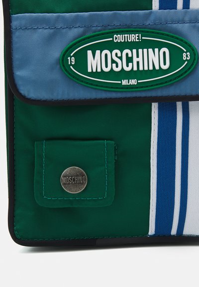 Geantă din nylon verde și albastru cu clapetă, model cu dungi și un buzunar frontal care are un logo metalic Moschino.