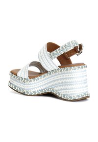 Kengät, joissa on sinivalkoinen raidallinen kangasyläosa, ruskea nahkapohja ja letitetty yksityiskohta pohjassa. Säädettävä nilkkahihna.