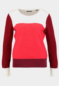 Jersey de punto con un diseño de bloques de color que presenta secciones en rojo, burdeos y crema. Cuello redondo y puños de canalé. Textura suave.
