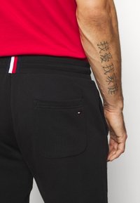 Schwarze Jogginghose mit einer Gesäßtasche und gesticktem Logodetail in Rot, Weiß und Blau. Elastischer Bund mit Streifenakzenten.