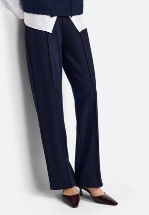 Pantaloni a gamba larga color navy realizzati in un tessuto liscio, con pences frontali. Abbinati a tacchi a punta bordeaux con una finitura testurizzata.