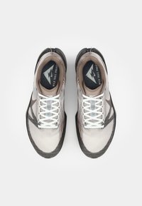 Chaussures de sport avec une tige en mesh respirant dans des tons gris et marron, lacets blancs, semelles en caoutchouc noires et un col rembourré.
