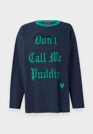 Lahti sininen pitkähihainen T-paita, joka on valmistettu puuvillasta ja jossa on vihreä koristeellinen teksti "Älä kutsu minua Puddingiksi" sekä vihreä sydämen muotoinen yksityiskohta.