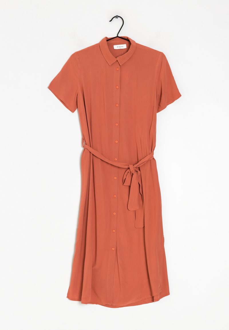 Robe à manches courtes couleur rouille avec boutons, col et ceinture nouée à la taille, suspendue sur un cintre noir sur fond blanc.