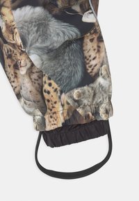 Kurtka z nadrukiem różnych kotów, o błyszczącej powierzchni, z elastycznymi mankietami oraz czarnym elastycznym sznurkiem u dołu.