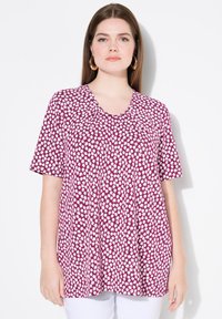 Top de manga corta en tela morada con estampado de margaritas blancas, escote en forma de barco y detalle plisado para un ajuste relajado.