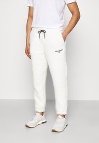 Vita, fluffiga fleece-joggers med elastisk midjeresår och dragsko, med "POLO SPORT"-logga i svart och rött på vänster lår.