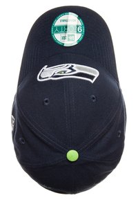 Gorra de béisbol azul marino con una pegatina circular verde y el logo bordado de los Seattle Seahawks en la parte frontal. Tela texturizada con visera plana.
