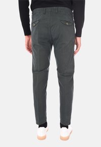 Pantaloni di cotone grigi con vestibilità slim, dotati di due tasche posteriori e dettagli con bottoni, abbinati a sneaker bianche.
