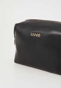 Borsa in pelle nera con superficie testurizzata e logo "LIU-JO" in tono oro. Include una chiusura con zip sulla parte superiore per una conservazione sicura.