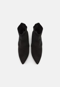 Stivali neri alla caviglia con punta appuntita, materiale in suede, parte superiore in maglia a coste e design aderente. Nessuna ferramenta o decorazione visibile.