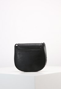 Czarna skórzana torebka crossbody o zaokrąglonym kształcie, o fakturowanej powierzchni i z klapką na zapięcie. Minimalistyczne okucia z przeszyciami na krawędziach.